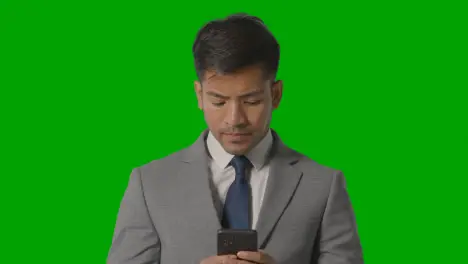 Studio Shot Of Frustrated Businessman In Suit Against Green Screen Looking At Mobile Phone 