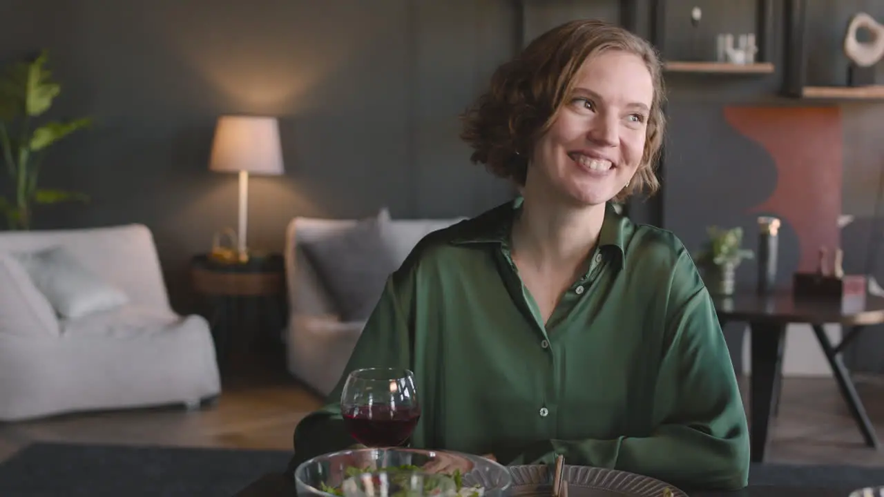 Retrato De Una Mujer Bonita Sonriente Sentada En La Mesa De La Cena Hablando Y Luego Brindando A La Cámara Con Una Copa De Vino Tinto