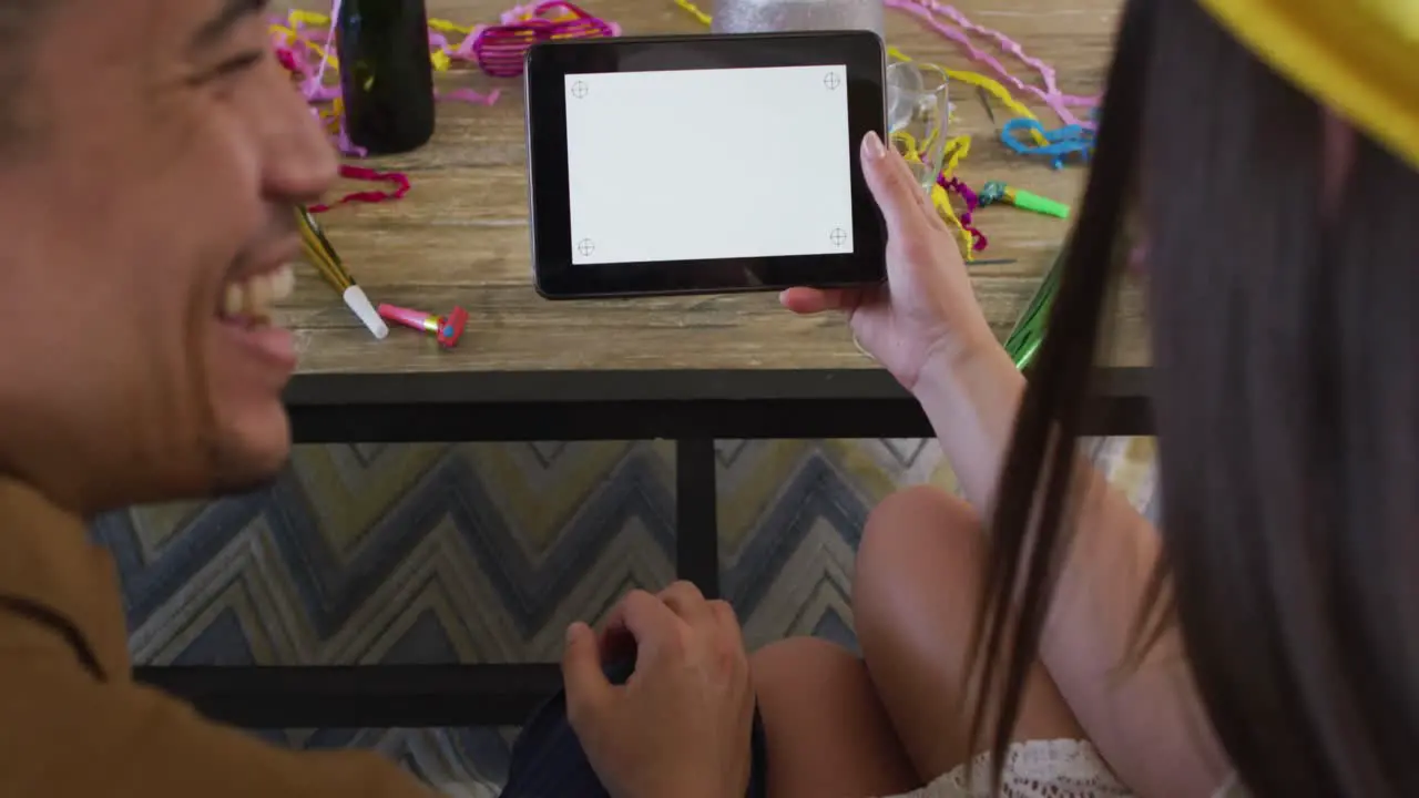 Happy biracial couple making celebration tablet video call with copy space on screen