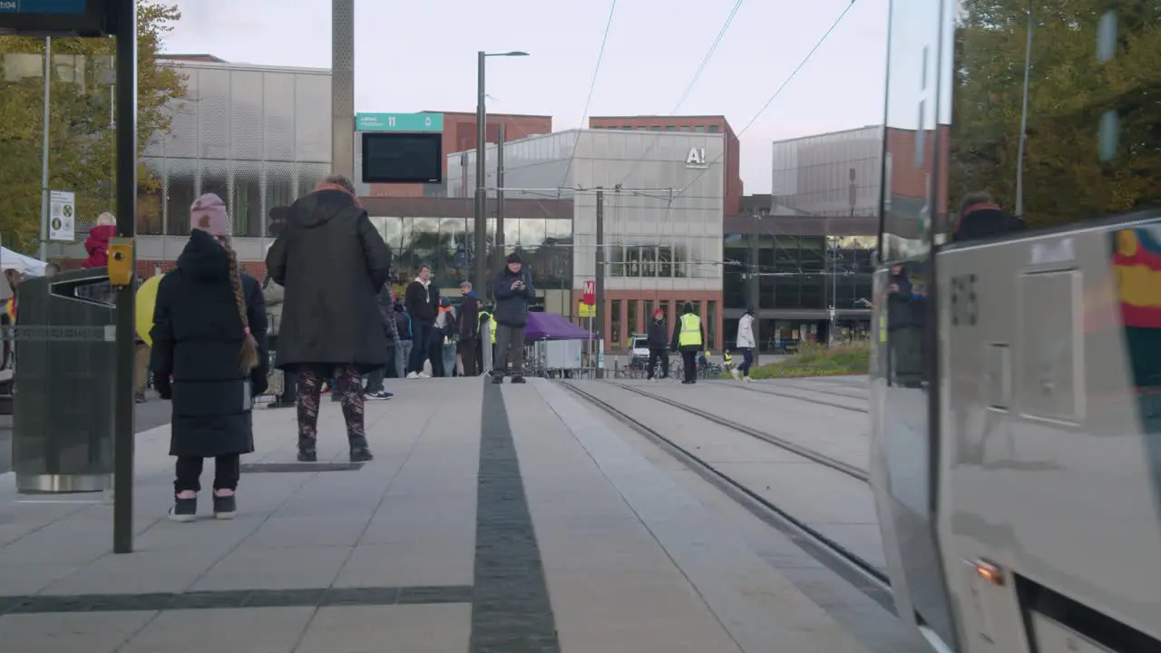 Commuter train leaves passengers on platform on autumn Helsinki street