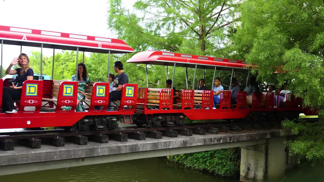 New Orleans USA April 22nd 2023 a bright red train car is moving along the tracks with passengers wavy towards the camera at a local tourist attraction in New Orleans