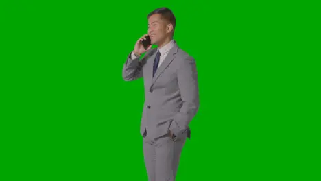 Three Quarter Length Studio Shot Of Businessman In Suit Taking Mobile Phone Call Against Green Screen 2