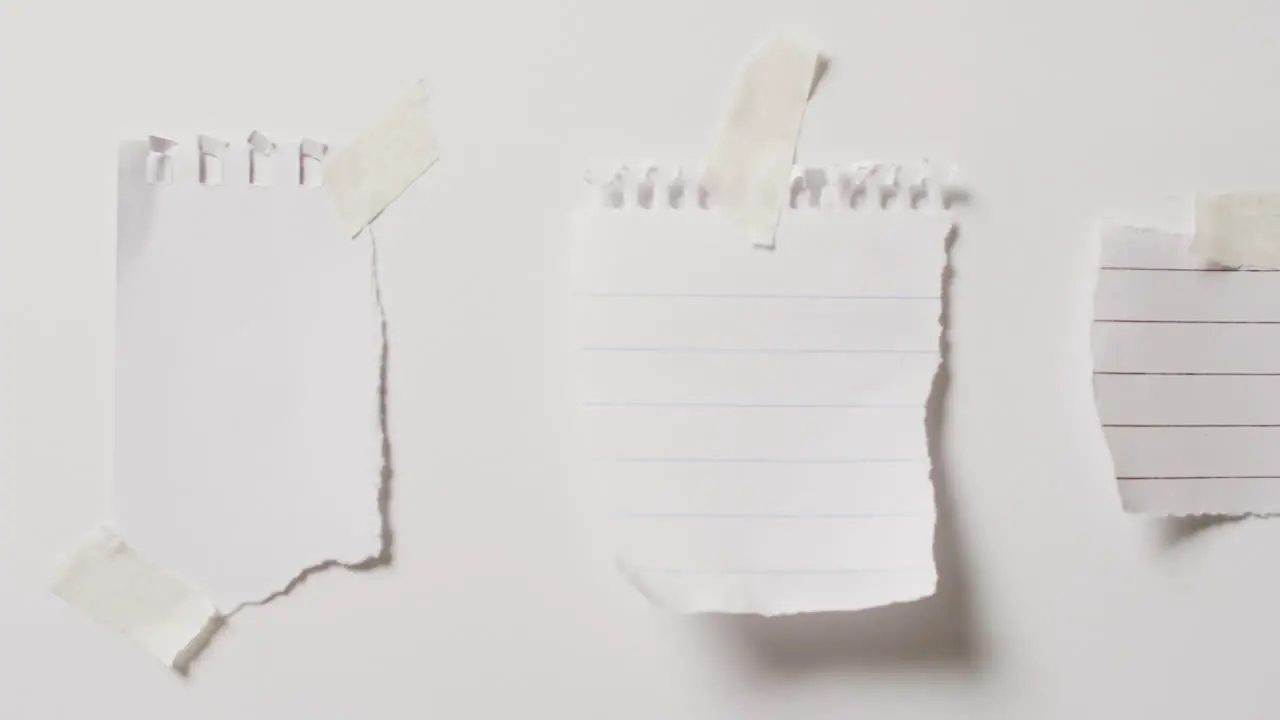 Video of close up of three scraps of paper with copy space taped on white background