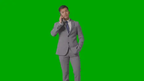 Three Quarter Length Studio Shot Of Businessman In Suit Taking Mobile Phone Call Against Green Screen 1