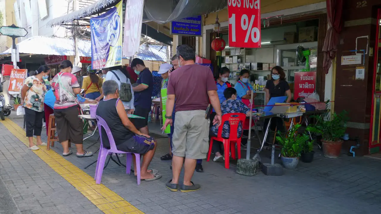 Shot of locals crowding towards the tables to buy lottery tickets in Songkhla Province Thailand at daytime