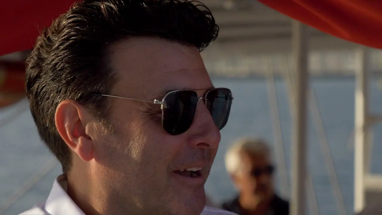 Man talking to someone else on a catamaran sail boat in the Mediterranean