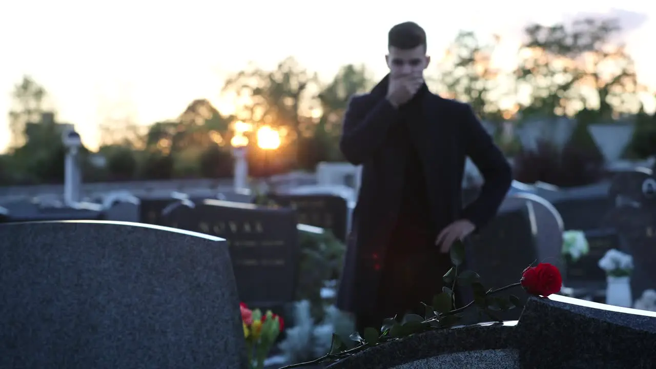 Sad man standing in front of a grave during sunset 4k footage