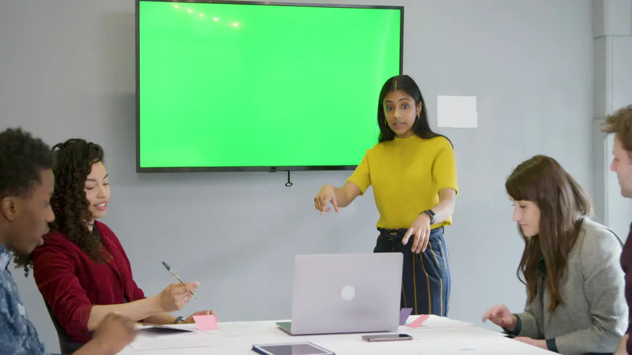 Woman Leading Meeting Colleagues With Green Screen Tv