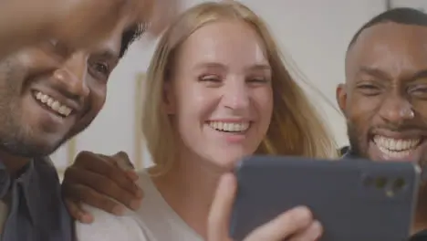 Multi-Cultural Friends Celebrating Watching Sports Game On Mobile Phone Sitting On Sofa At Home Together 6