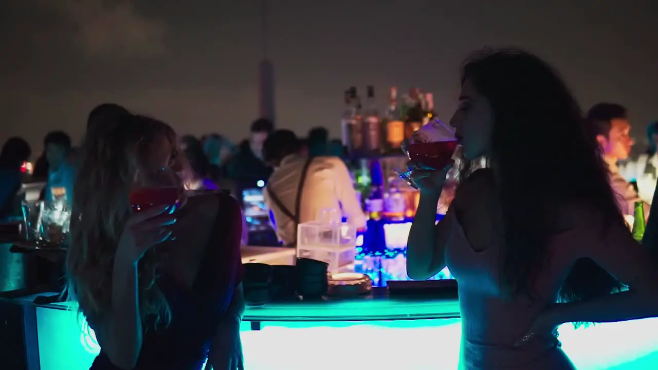 Medium shot Women having glass toasting in Thailand Octave Rooftop Bar People Partying and Bartender in the background