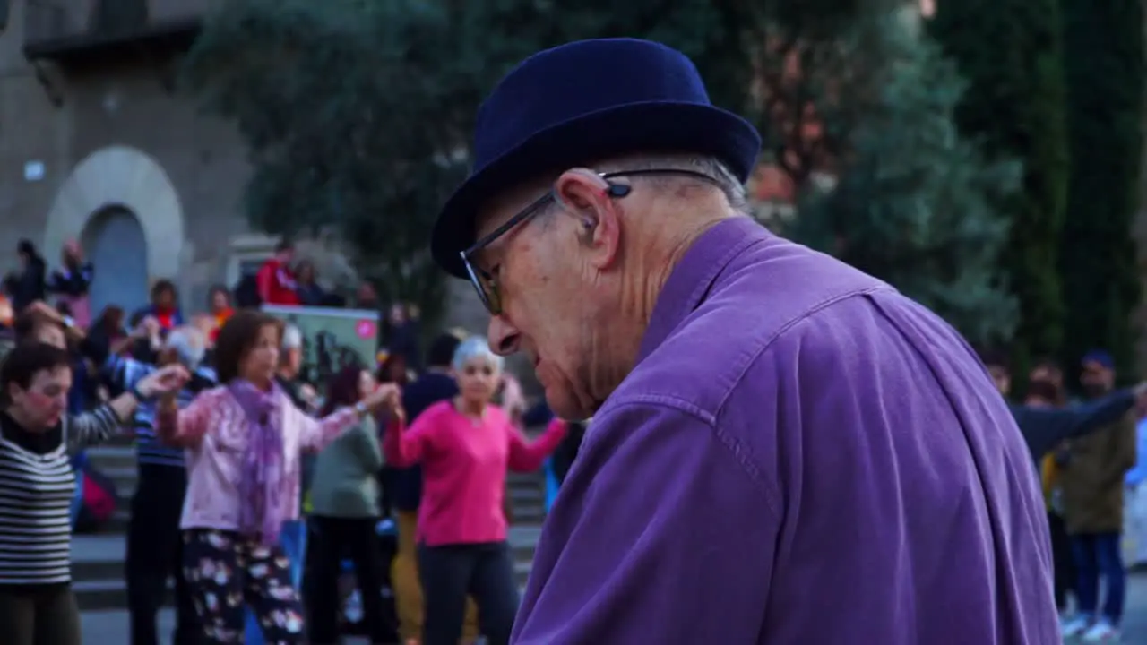 Senior Man Approaches Women and Hold her Hand Senior People jumping and dancing in the background together