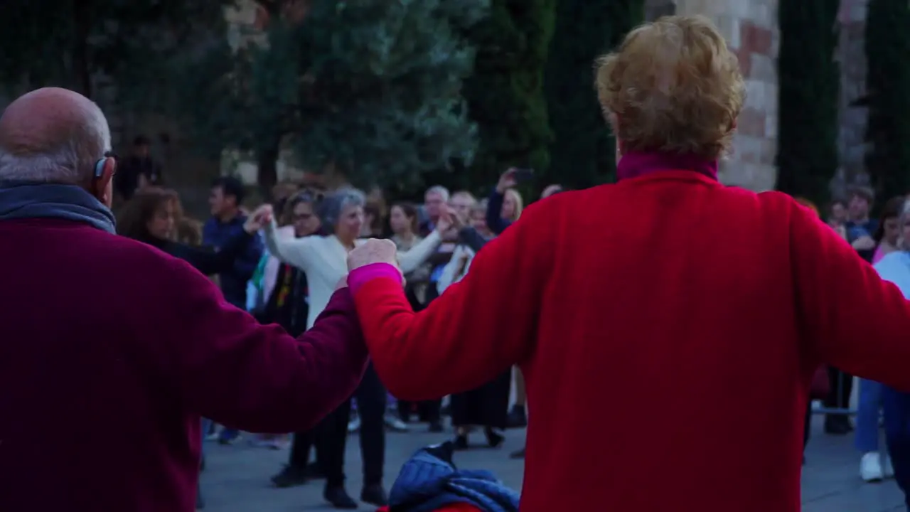 Panning Shot Elderly People Holding Hands in Traditional Dance Sardana in Plaza Nova Barcelona Spain Elderly People in the background