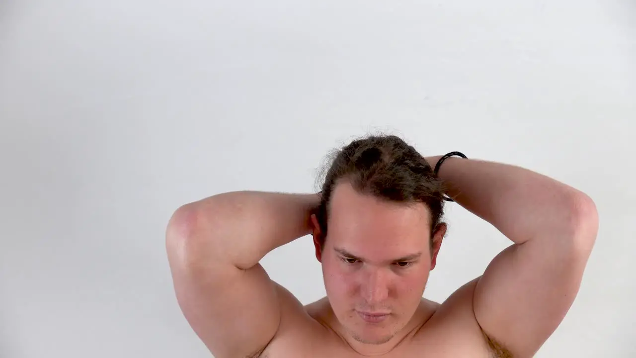 Young white man with blond hair without t shirt showing how he combs his hair without a mask in closeup with white background