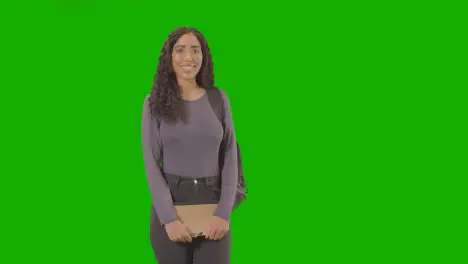 Portrait Of Female College Or University Student With Backpack And Notebook Against Green Screen Smiling At Camera 1