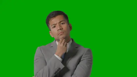 Portrait Of Serious Businessman In Suit Thinking Against Green Screen Looking At Camera