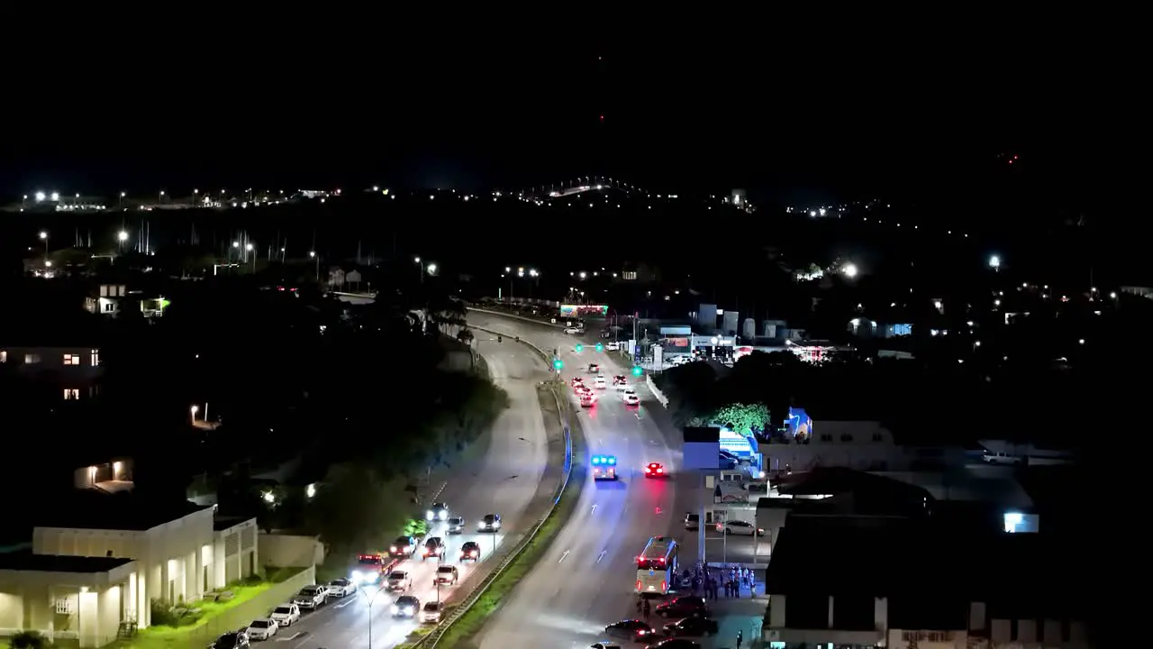 Flashing blue lights from ambulance reflect on city buildings as it drives to emergency aerial tilt up