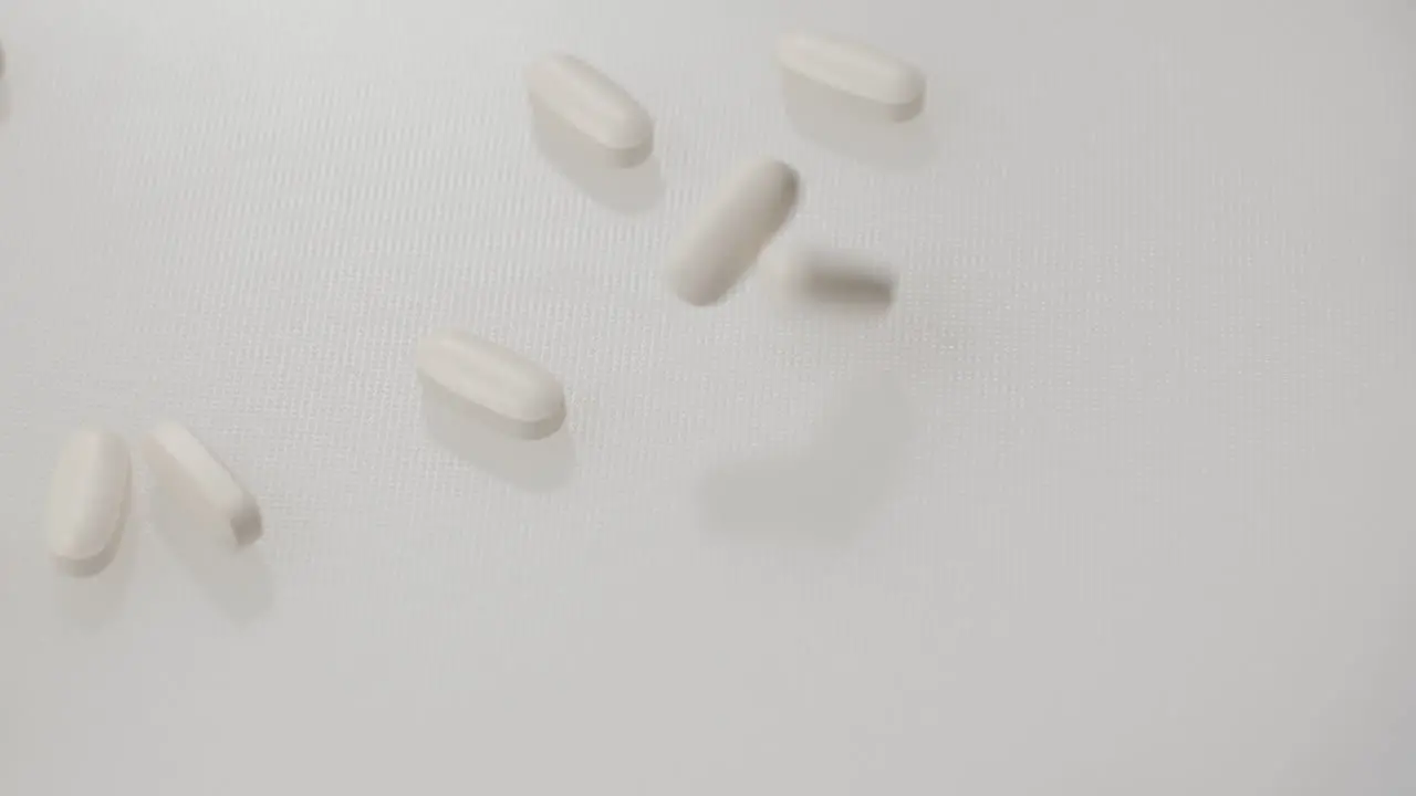 Pills falling on a white surface in slow motion