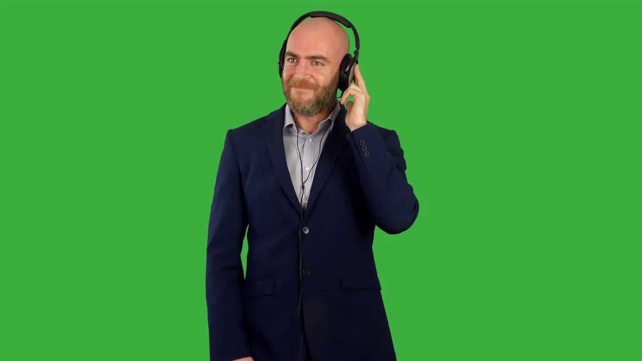 A businessman listinging to music on headphones and dancing on green screen