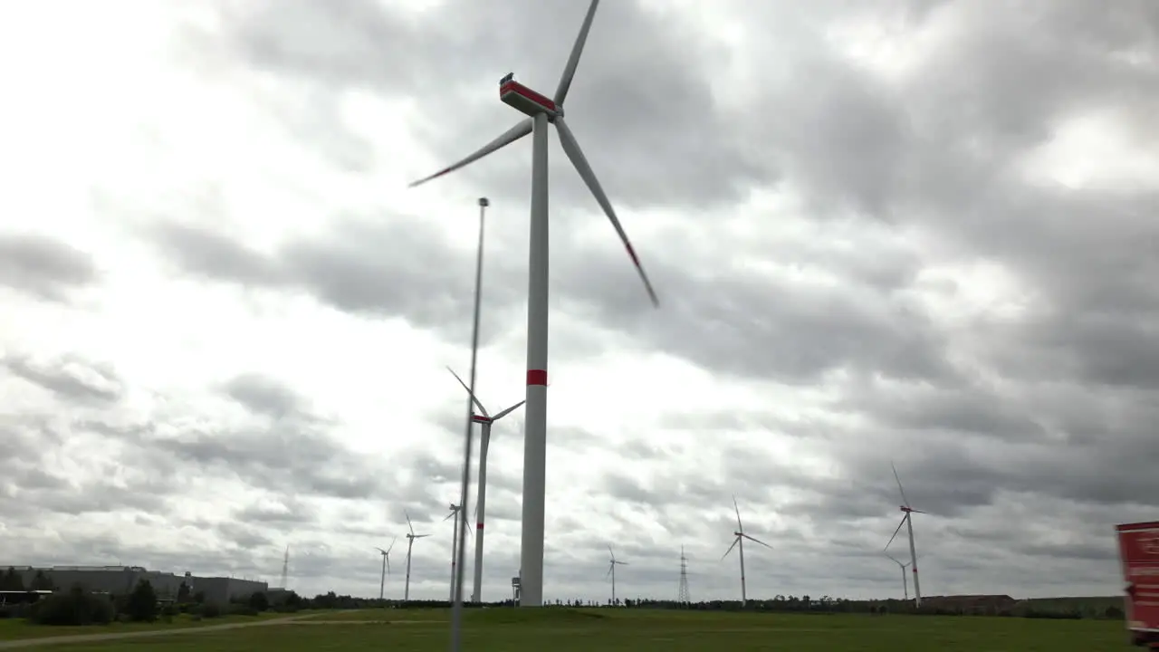 Wind turbines spinning against grey moody sky view from driving car