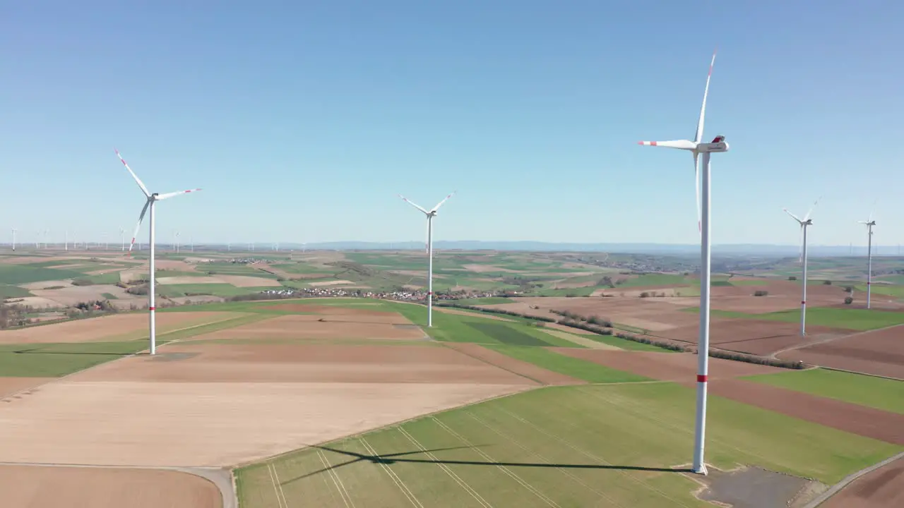 Rotating wind power plant producing renewable green clean engergy electricity in a wind farm on a sunny day drone aerial rotating panorama shot 25p