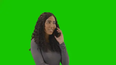 Woman Talking On Mobile Phone Against Green Screen Smiling And Laughing