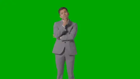 Three Quarter Length Shot Of Serious Businessman In Suit Thinking Against Green Screen