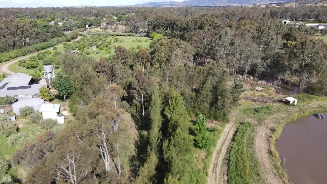 Drone aerial pan up over tree line on a permaculture farm with a dam in Victoria