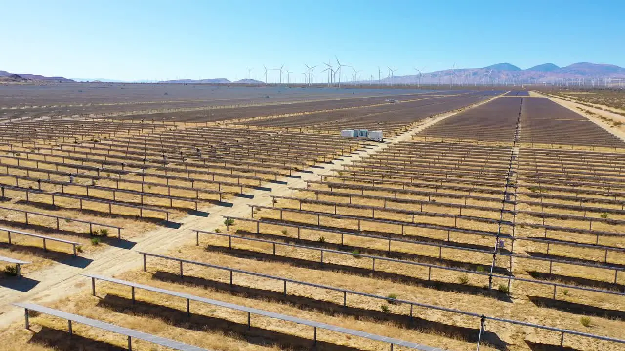 Aerial over a solar farm reveals a wind farm in the distance Mojave Desert California suggests clean renewable green energy sources