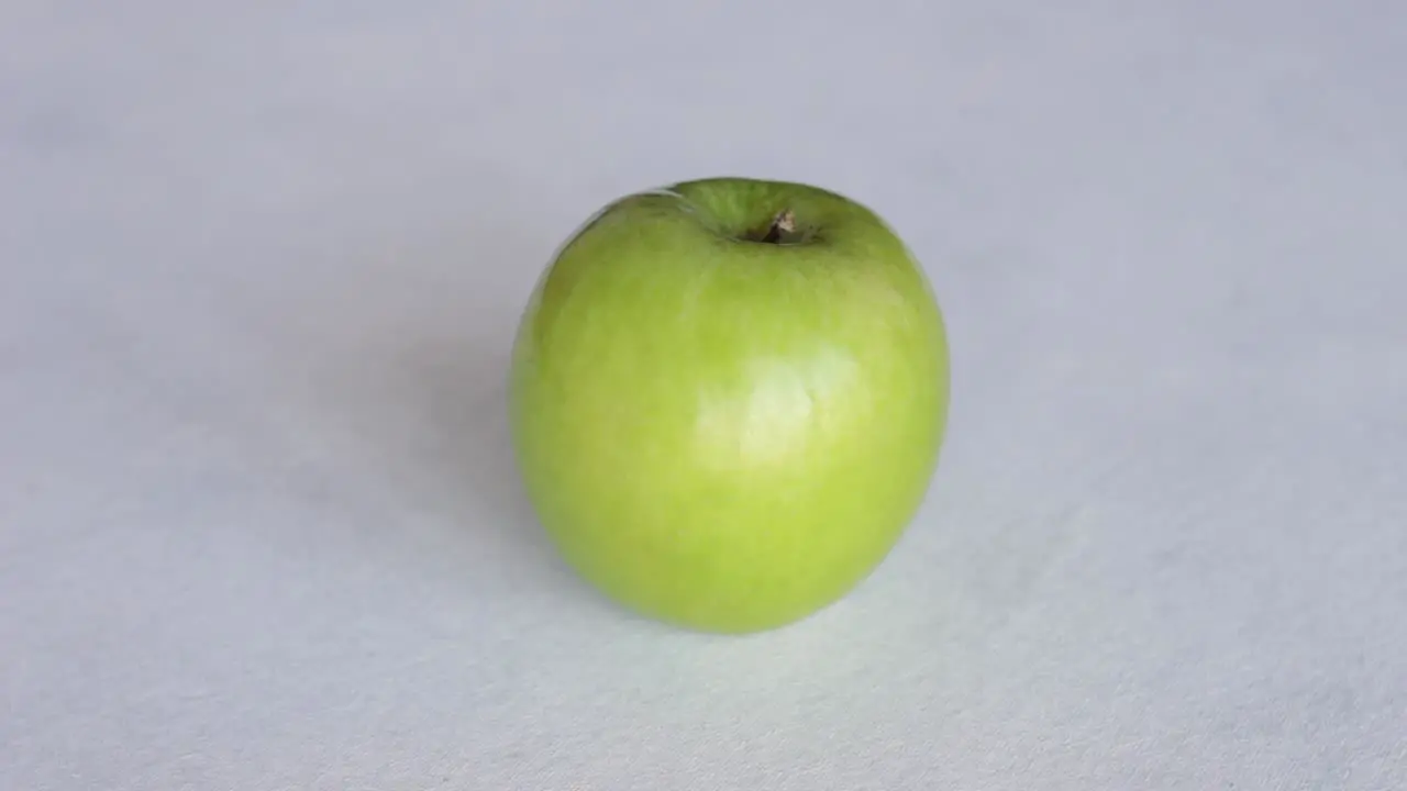 Hand Puts Fresh Green Apple On The Table