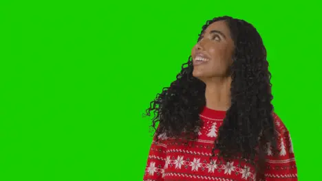 Studio Portrait Of Woman Wearing Christmas Jumper Against Green Screen With Hands Out To Catch Falling Snow 1