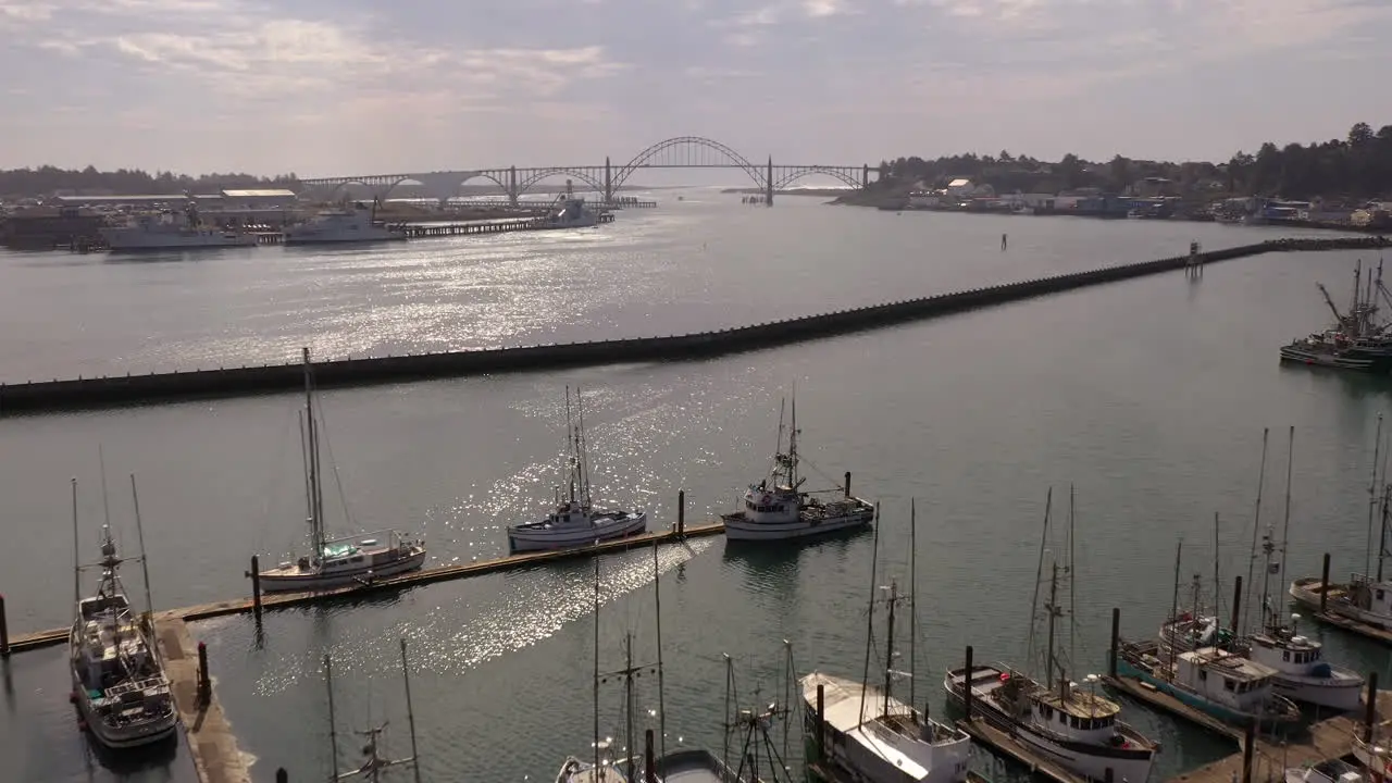 Newport Oregon wharf with moored boats and Yakina Bay Bridge in distance drone aerial view 4k