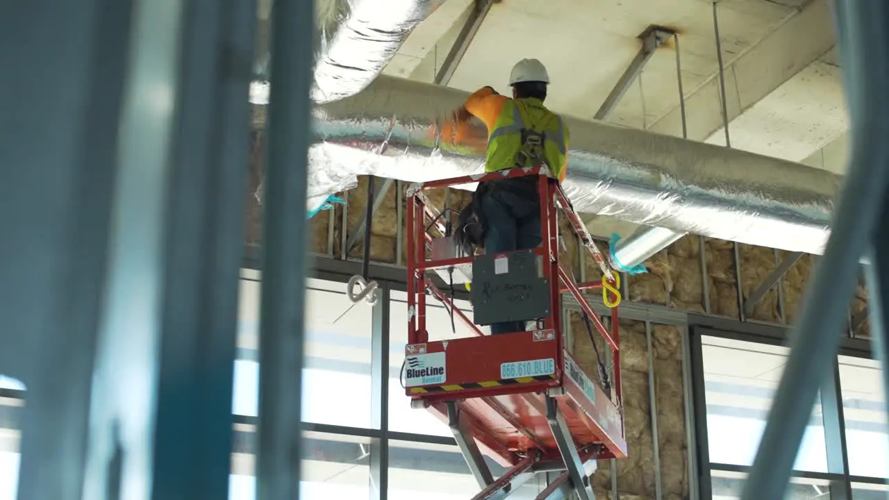 Pan of a construction worker on a man lift