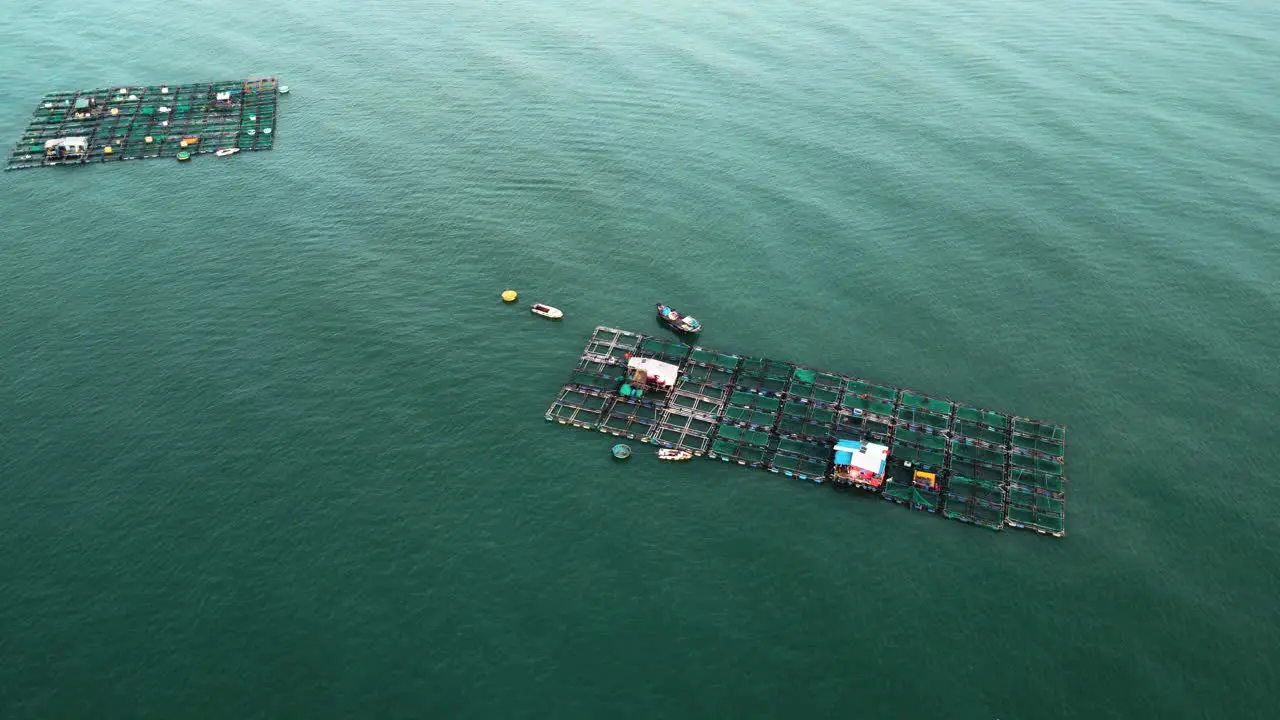 Aerial floating wooden fish farms floating in middle of rural ocean