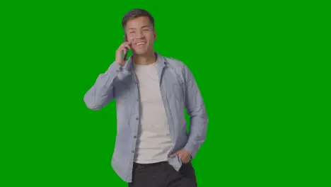 Studio Shot Of Casually Dressed Young Man Talking On Mobile Phone Against Green Screen 1