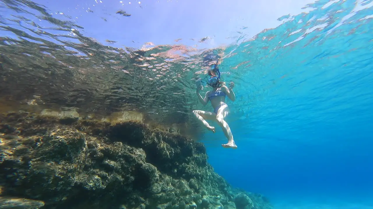 A young girl swims on the surface underwater view from below scuba diving on vacation