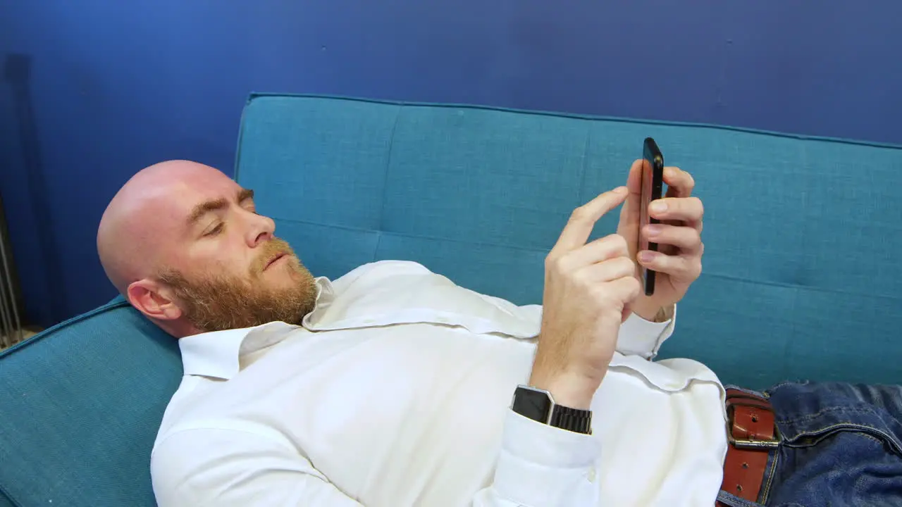 Close shot of man Lying On Sofa And Using Mobile Phone