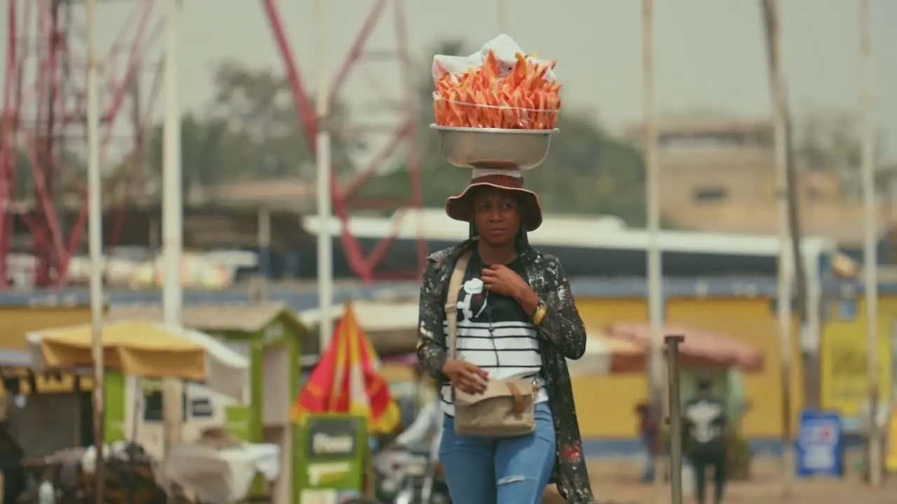 African Female Street Food Vendor Walking in slowmotion with Package on Head Togo Africa