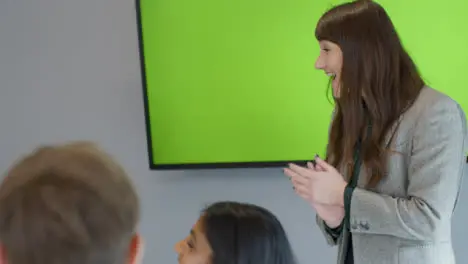 Happy Businesswoman Giving Presentation To Colleagues With Green Screen Tv