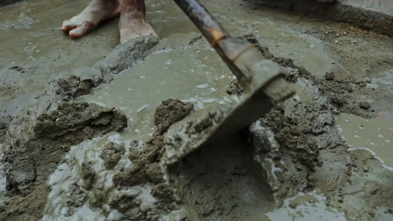 cement mixing in remote indian village construction site barefoot labor close up poor unsafe working condition concept