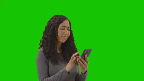 Woman Waiting Looking At Mobile Phone Against Green Screen