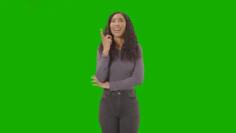 Three Quarter Length Portrait Of Woman Being Inspired By Good Idea Against Green Screen At Camera