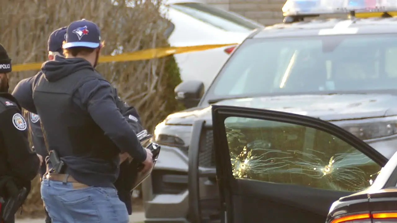 Uniformed and plain clothes police officer investigate another shooting in the Canadian city of Toronto