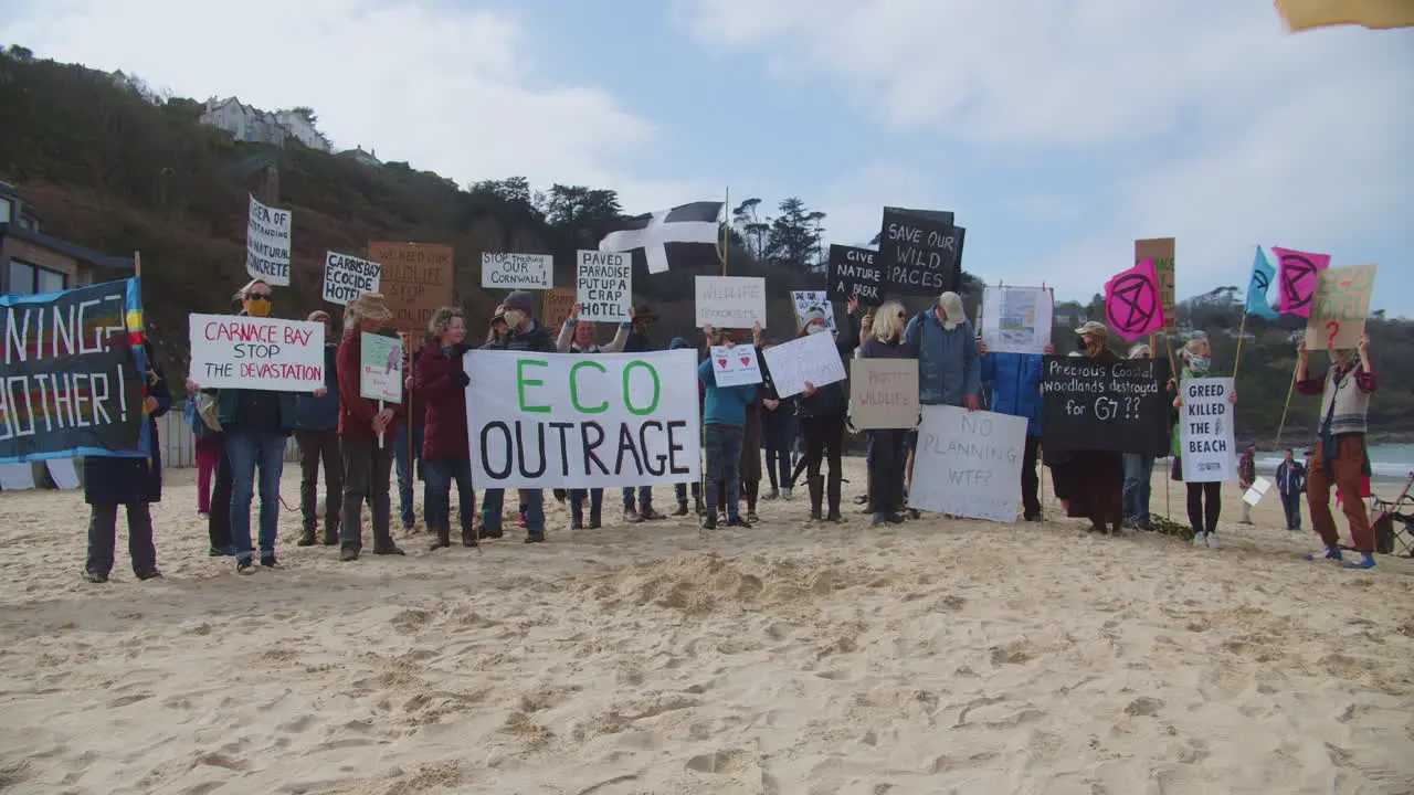 Numerous protesters gather together on the beach in front of the Carbis Bay Hotel in St Ives Cornwall