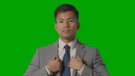 Portrait Of Serious Businessman Doing Up Suit Jacket Against Green Screen Looking At Camera 1