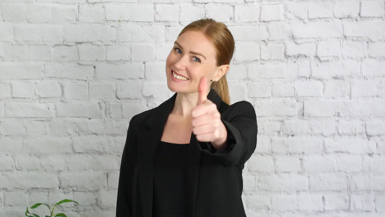 A businesswoman giving a thumbs up hand gesture The girl raises her thumb and smiles