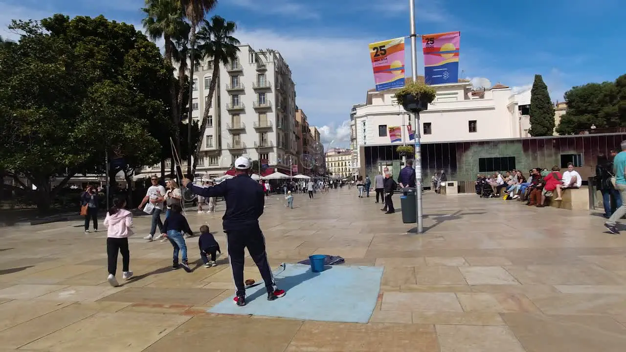 Male street busker creating soap bubbles to play with kids on public street