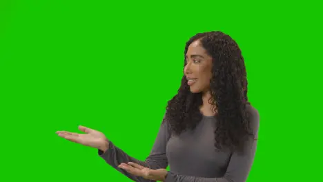 Portrait Of Woman Presenting Or Demonstrating Item Against Green Screen Smiling At Camera 1