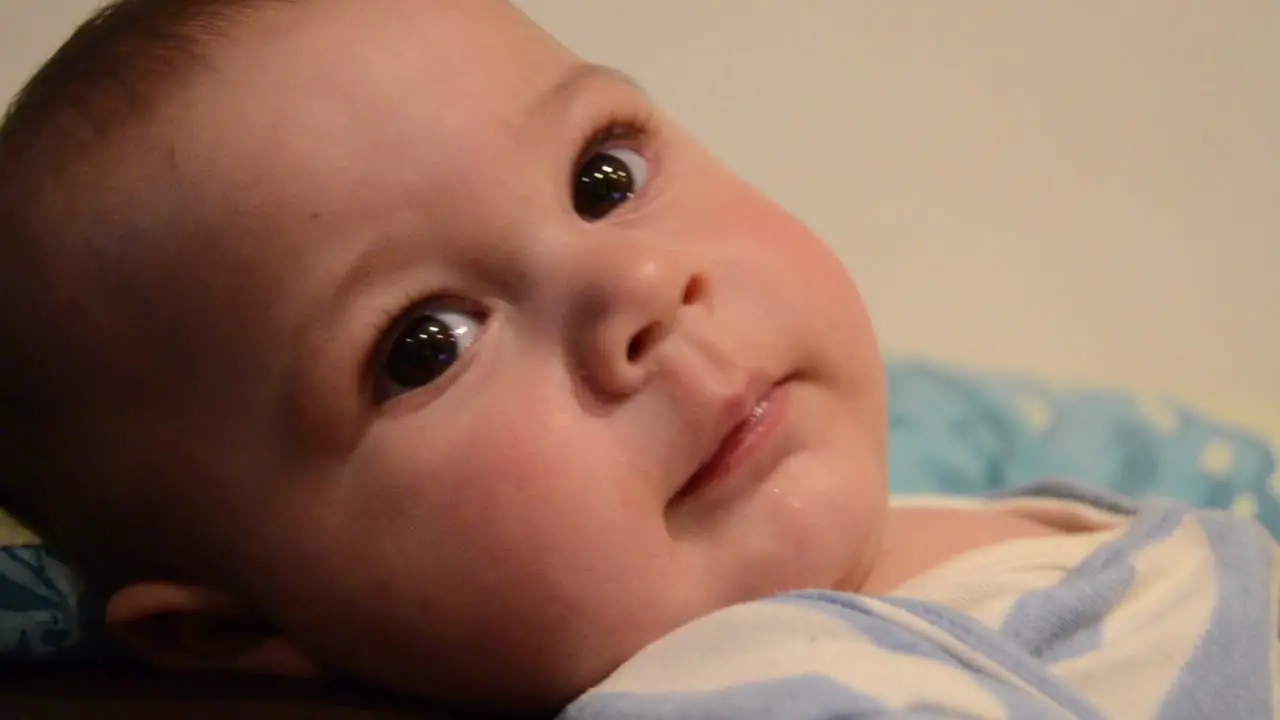 close up overhead shoot of baby boy lookig at the camera and trying to reach it