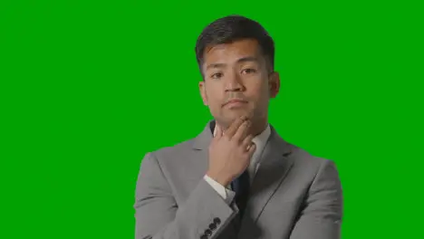 Portrait Of Serious Businessman In Suit Thinking Against Green Screen Having Idea