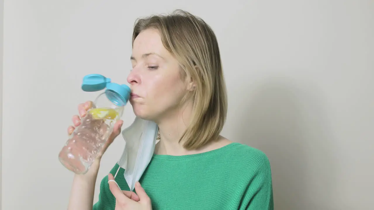 A woman has to remove her PPE mask before she can drink from her water bottle